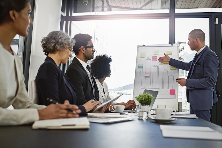 A man presenting at a flip chart to colleagues seated at a table