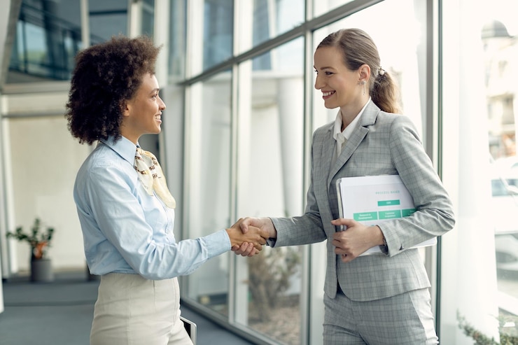 Two women shaking hands in a bright office