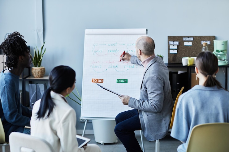 A man writing on a whiteboard while colleagues follow along